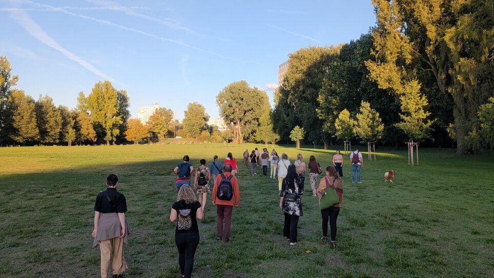 Eine Gruppe von Menschen geht auf einem grünen Feld im Park. | © Toby Mayra