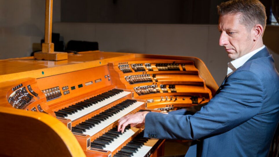 A man in a suit plays an organ with a wooden surface. | © Sandra Wolf