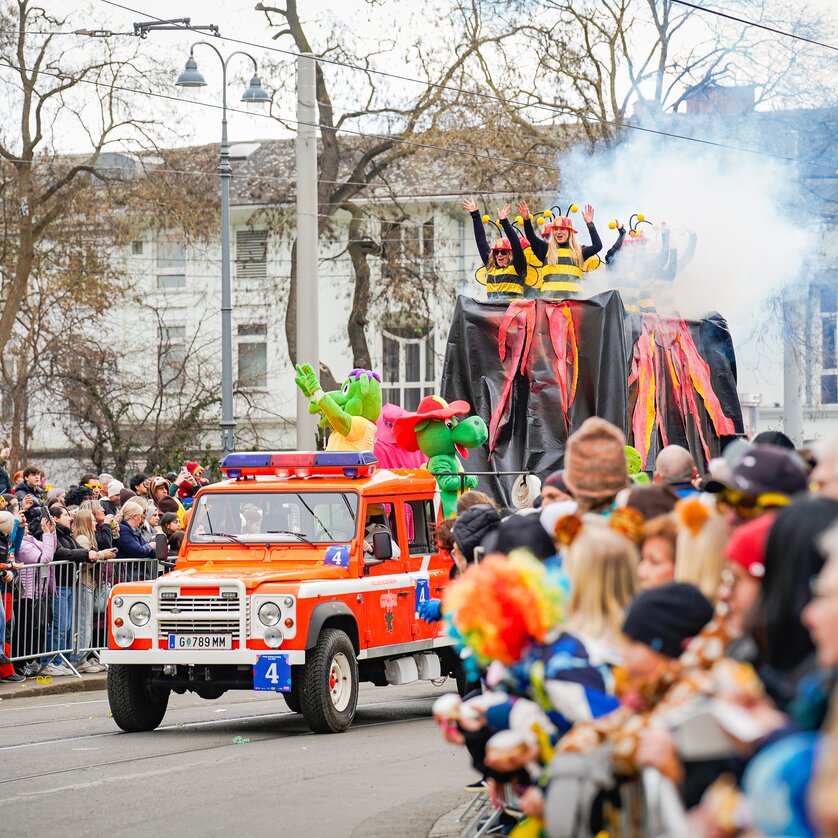 Colorful carnival parade featuring costumed performers and a fire truck. | © Thomas Klier