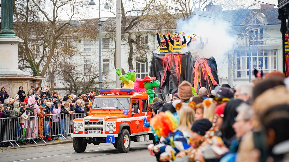 Colorful carnival parade featuring costumed performers and a fire truck. | © Thomas Klier