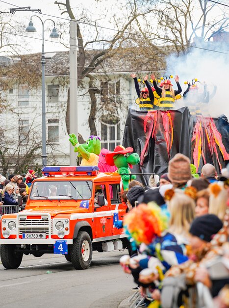 Colorful carnival parade featuring costumed performers and a fire truck. | © Thomas Klier
