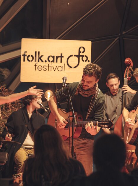 Fünf Musiker mit Gitarren, Kontrabass und Schlagzeug spielen auf einer Bühne | © Madelaine-Marie