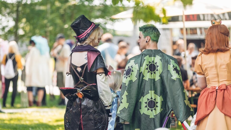 Three cosplayers stand in the green outdoor area of the Seifenfabrik Graz | © Hanamicon - Paul Andrews