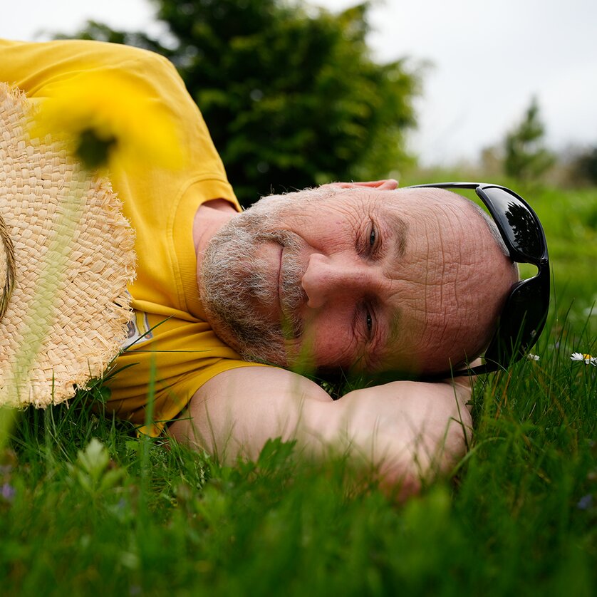 Entspannter Mann auf dem Gras, trägt einen Strohhut und lächelt. | © Tom Lachmayr
