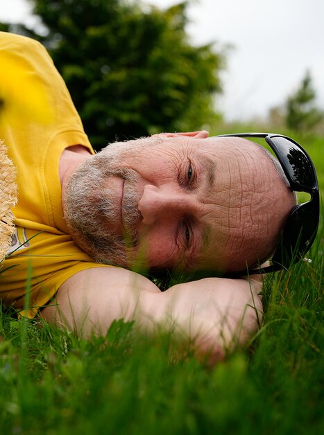 Entspannter Mann auf dem Gras, trägt einen Strohhut und lächelt. | © Tom Lachmayr