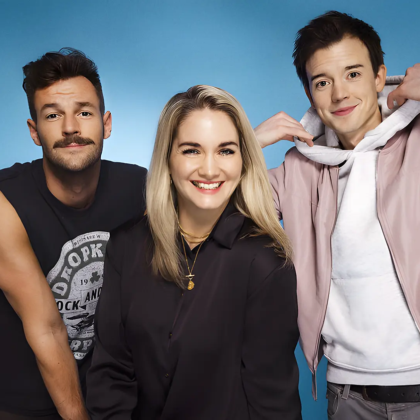 Paul Pizzera, Gabi Hiller & Philipp Hansa | © Moritz Schell Drei Personen posieren vor einem blauen Hintergrund und lächeln. | © Moritz Schell