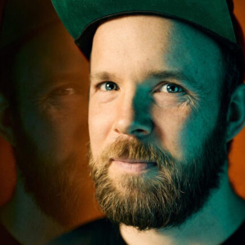 Porträt eines Mannes mit grüner Kappe und Bart vor warmem Hintergrund. | © Marvin Ruppert