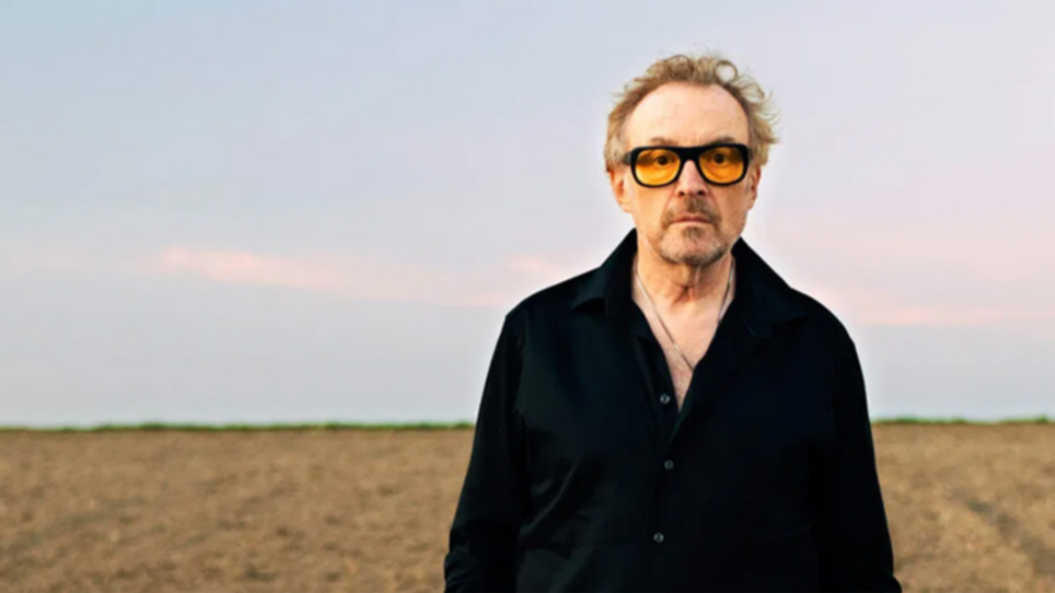 Ein Mann mit Sonnenbrille steht in einem offenen Feld unter einem Himmel. | © Lukas Beck