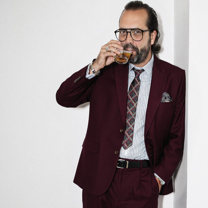 Mann mit Bart, Brille und rotem Anzug, der Whisky trinkt. | © MediaFly