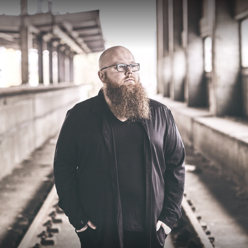 Ein Mann mit Bart und Brille steht in einem industriellen Raum. | © Universal Music