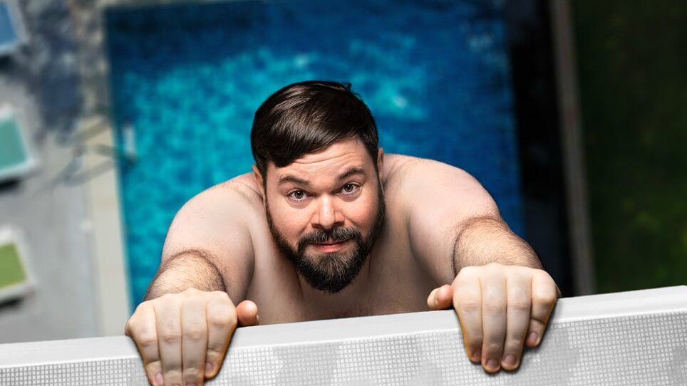 Ein Mann mit Bart hängt an einem Rand, über einem blauen Pool. | © Jan Frankl