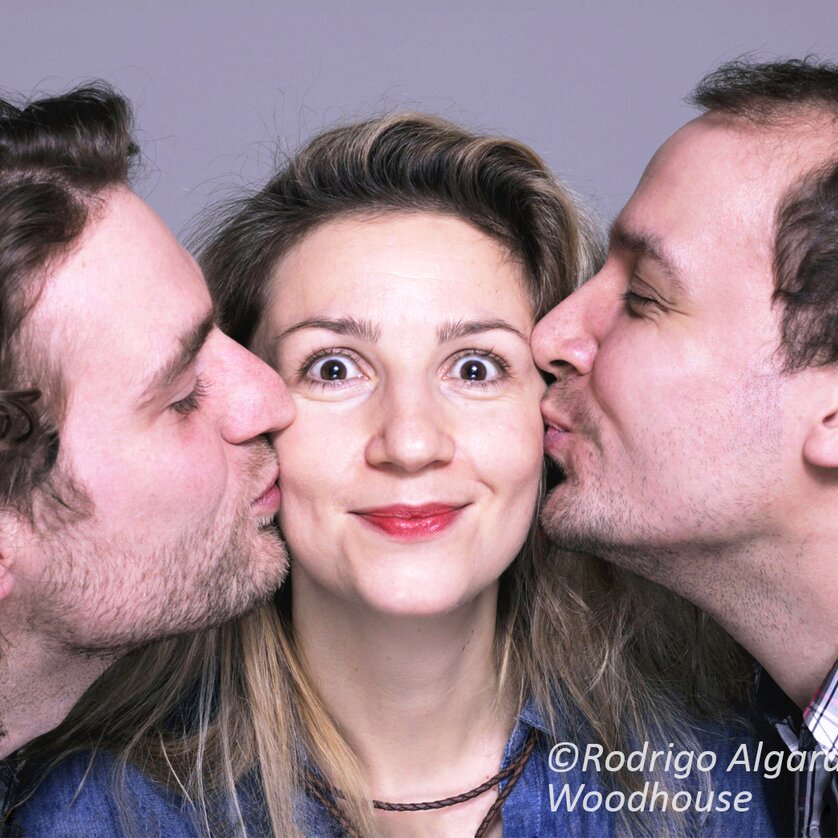 Zwei Männer küssen eine Frau von beiden Seiten, die überrascht schaut. | © Rodrigo Algara Woodhouse
