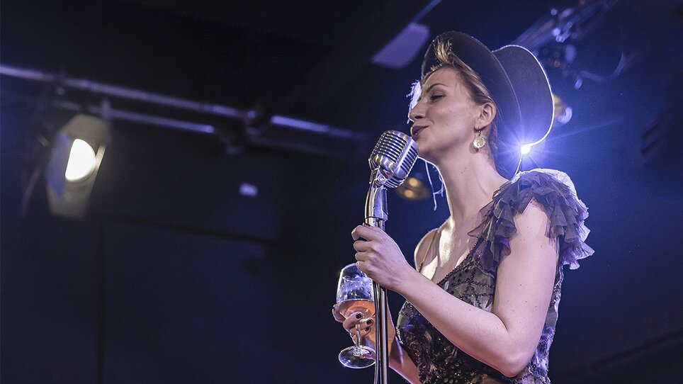A woman with a microphone and drink in a jazz club. | © Lucija Novak
