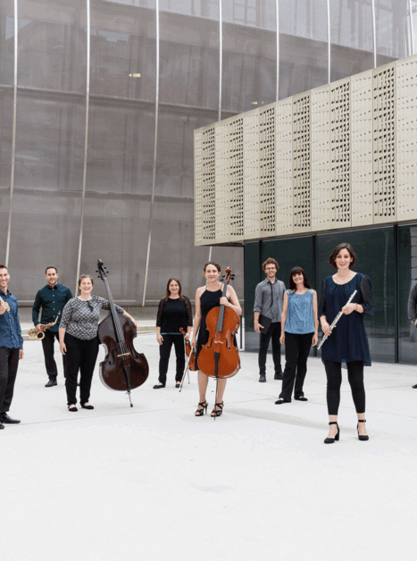 a group of musicians with their instruments stands in front of a modern building | © Maria Frodl