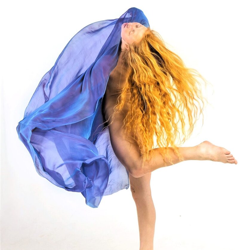 Internationale Bühnenwerkstatt Veza Fernandez | © Lotta Sandbergh Tanzende Frau mit langem rotem Haar, gehüllt in fließenden blauen Stoff, auf weißem Grund | © Lotta Sandbergh