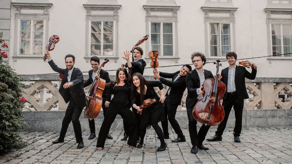 Ein Ensemble in eleganten Outfits posiert lebhaft im Freien. | © Marija Jancic