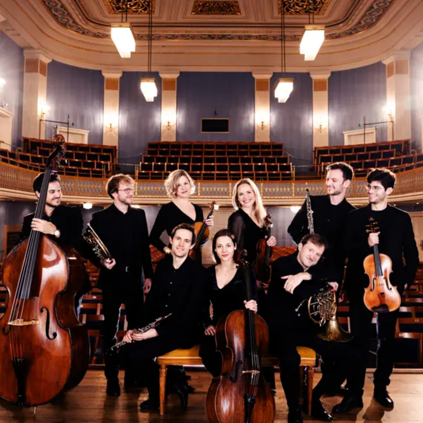 Ein Musikensemble posiert im Konzertsaal mit verschiedenen Instrumenten. | © Julia Wesely
