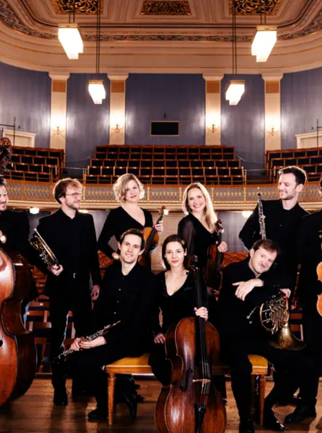 Ein Musikensemble posiert im Konzertsaal mit verschiedenen Instrumenten. | © Julia Wesely