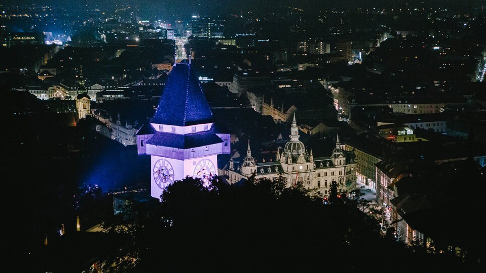 Illuminated city of Graz at night with the Graz Clock Tower in the foreground. | © Sebastian Reiser