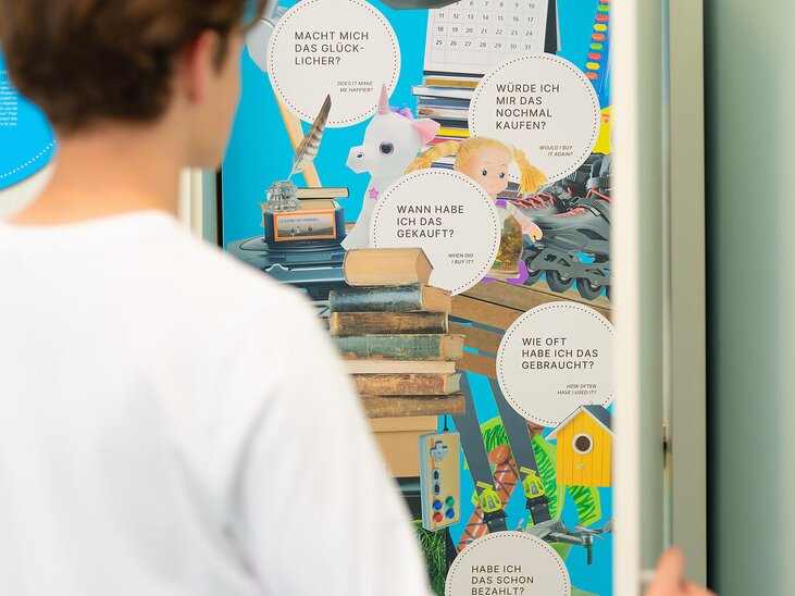 Eine Person betrachtet eine Schranktür mit Fragen zum Konsumverhalten. | © stella