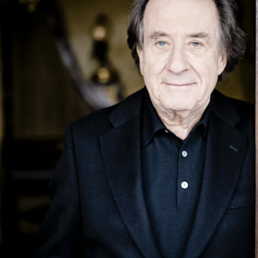 Rudolf Buchbinder | © Marco Borggreve Ein älterer Mann in schwarz gekleidet, lächelt leicht und steht in einer eleganten Umgebung. | © Marco Borggreve