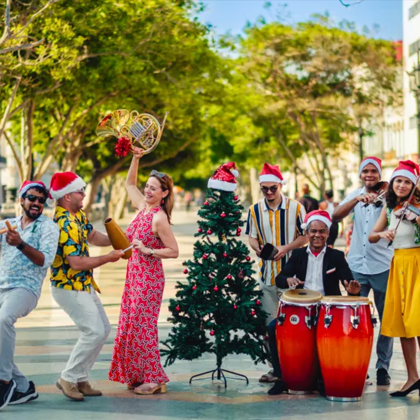 Gruppe von Menschen feiert Weihnachten mit Musikinstrumenten und einem Weihnachtsbaum. | © Victor Cervantes