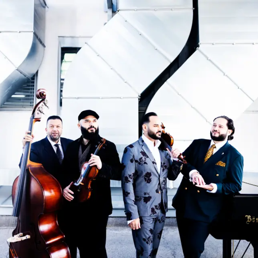 Vier Musiker posieren mit Instrumenten vor einer modernen Architektur. | © Julia Wesely