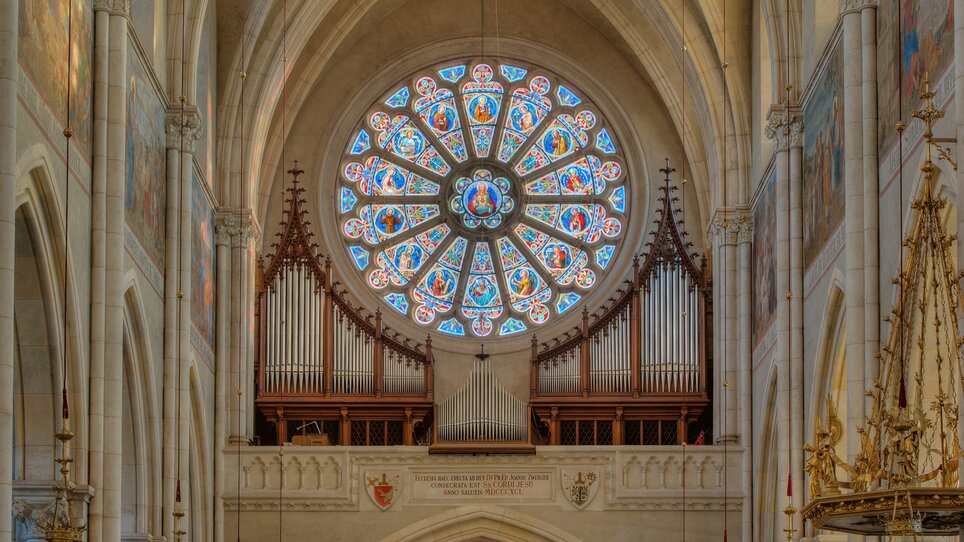 View of a church interior featuring a colorful rose window and an organ. | © Guenther-Deutsch