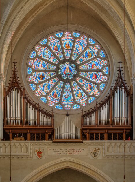 Blick auf einen Kirchenraum mit einem bunten Rosettenfenster und einer Orgel. | © Guenther-Deutsch