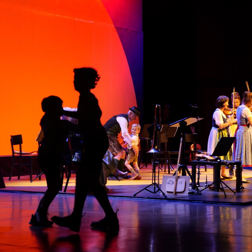 Tanzende Menschen im Schatten, während Musiker auf der Bühne spielen. | © Styriarte - ct