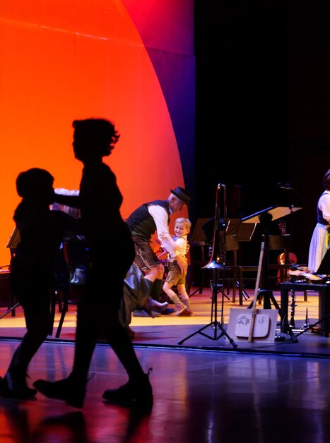 Dancing people in silhouette while a band performs on stage. | © Styriarte - ct