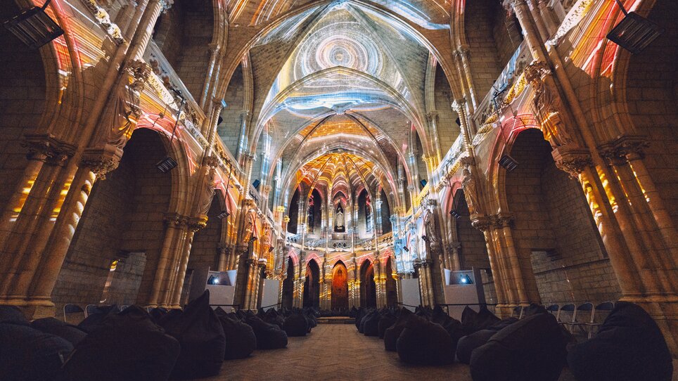 Blick ins Innere einer alten Kirche mit Lichtprojektionen. | © Projektil