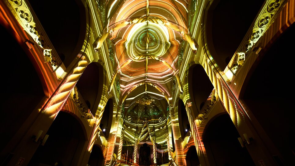 Farbige Lichtprojektionen an der Kirchenkuppel und Wänden. | © Projektil