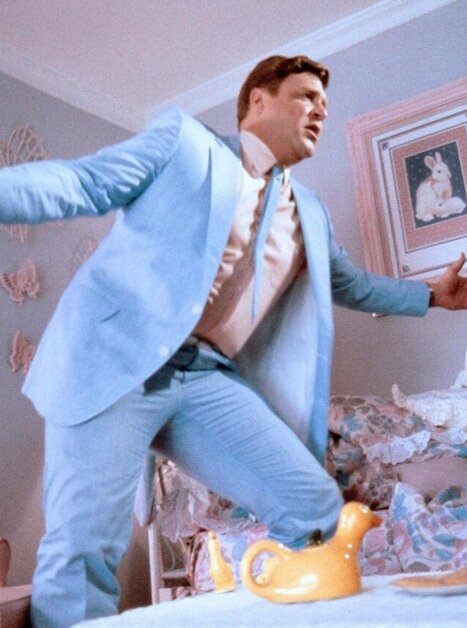 Man in light blue suit performs in a room with pastel-colored walls. | © 1986 Warner Bros. - Jonathan Demme