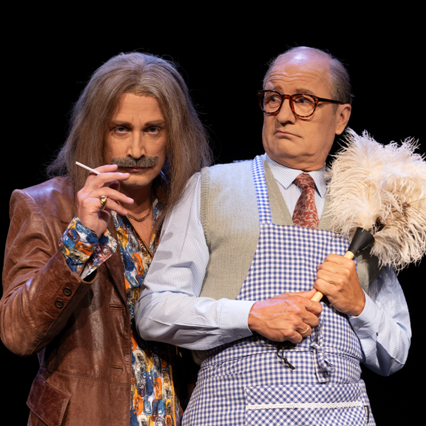 Zwei Männer in verrückten Outfits und mit Requisiten in einer Bühnenaufführung. | © Komödie Graz