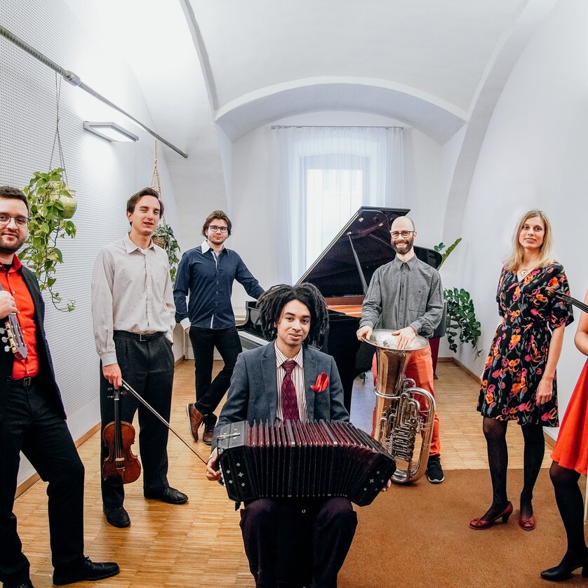 Eine Gruppe von Musikern posiert mit ihren Instrumenten in einem hellen Saal. | © Tobias Kochseder