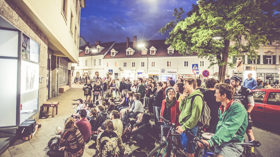 Menschen versammeln sich beim Lendwirbel neugierig vor einem Bildschirm im Freien. | © Lupi Spuma