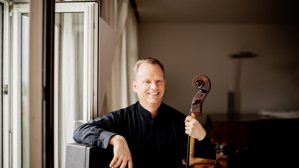 Ein Cellist posiert mit seinem Instrument in einem Raum. | © Julia Wesely