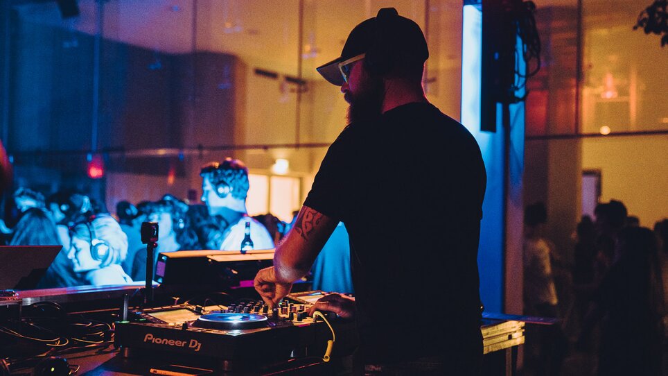 Ein DJ spielt Musik bei einer Silent Disco Veranstaltung mit bunten Lichtern. | © Silent Disco Austria
