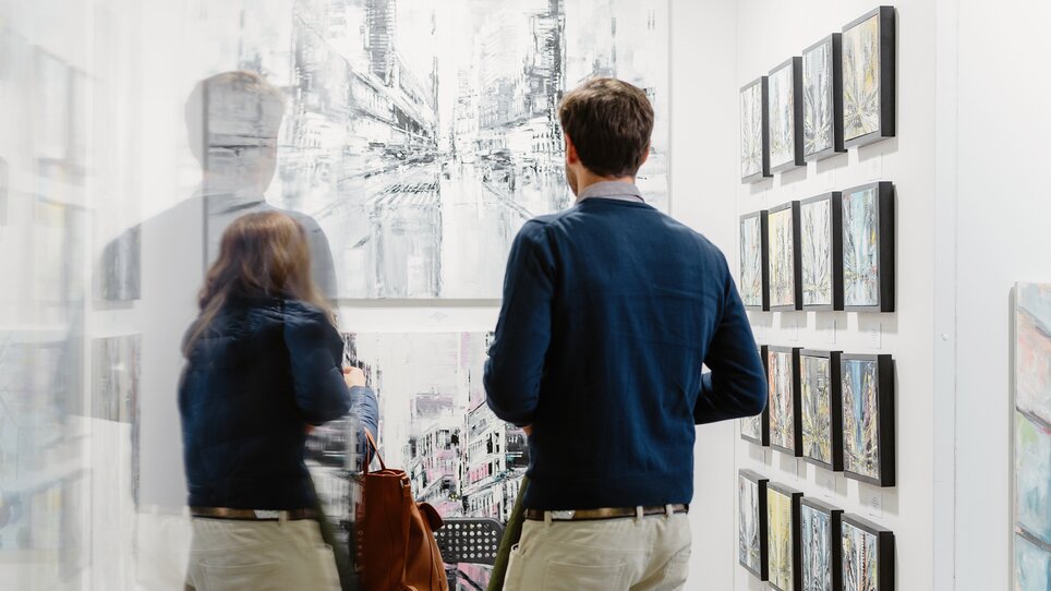 Two people are looking at pictures at the Art Expo. | © Katja Čemažar