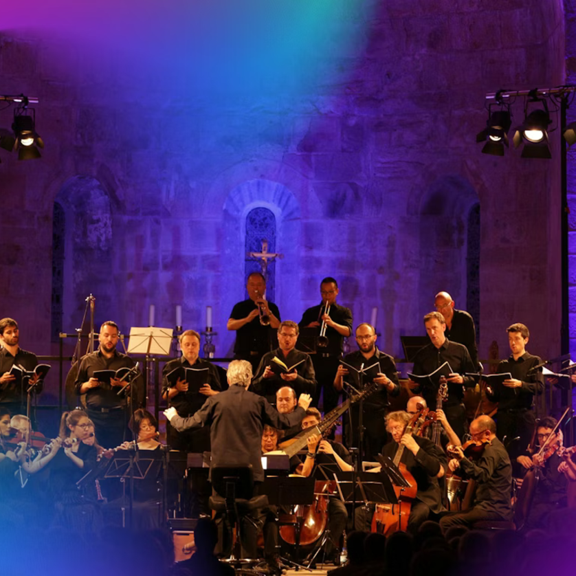 Ein Orchester spielt unter Anleitung eines Dirigenten in einer beleuchteten Kirche. | © pouyfourcat