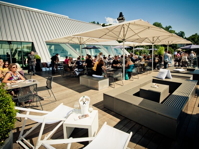 Menschen genießen die Sonne auf einer modernen Dachterrasse in Graz.