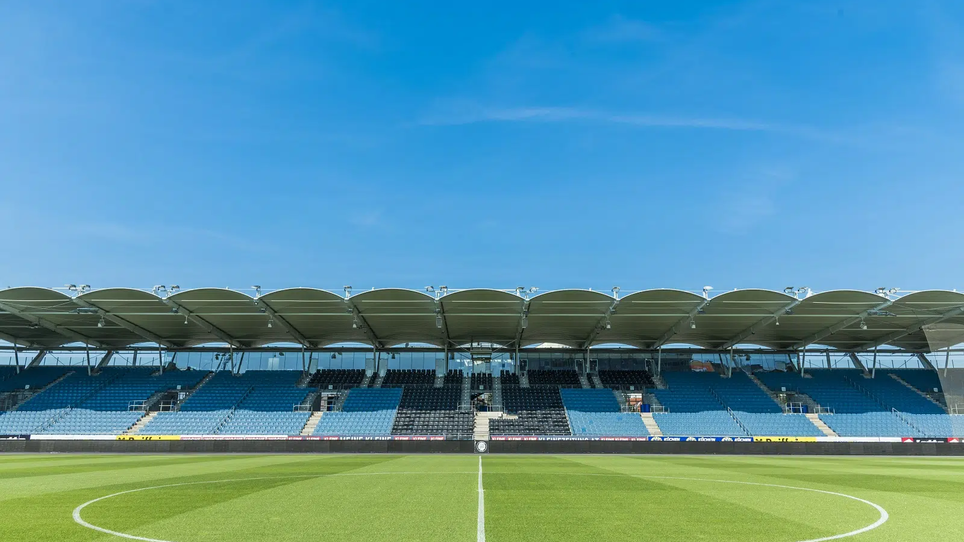 Weite Sicht auf die MERKUR Arena Graz mit klarem Himmel und gepflegtem Rasen.