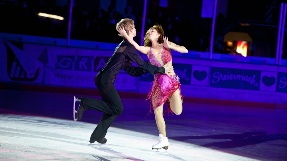 Ein Paar in glamouröser Kleidung beim Eiskunstlaufen auf Bühne. | © MCG - Martin Wiesner