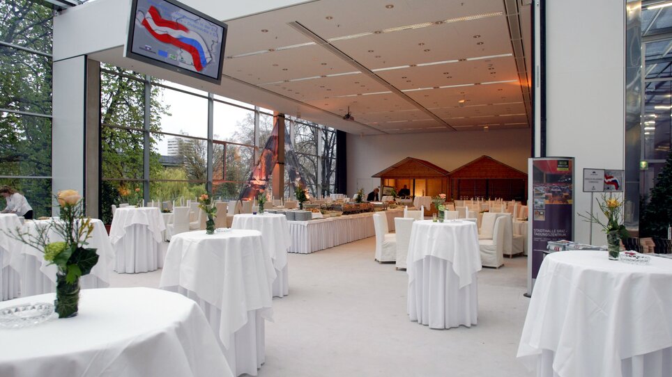 Elegant event space featuring round tables and catering area. | © MCG