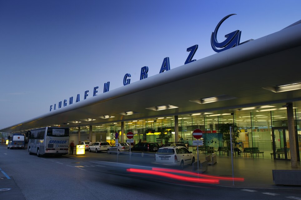 Flughafen Graz: Modern und einladend | © Graz Tourismus - Harry Schiffer Der Flughafen Graz mit modernen Architekturelementen, beleuchtet bei Dämmerung. | © Graz Tourismus - Harry Schiffer