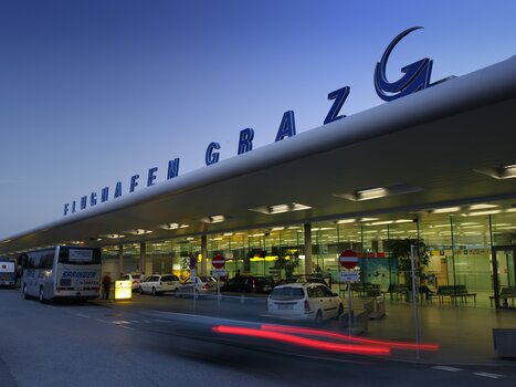 Der Flughafen Graz mit modernen Architekturelementen, beleuchtet bei Dämmerung. | © Graz Tourismus - Harry Schiffer
