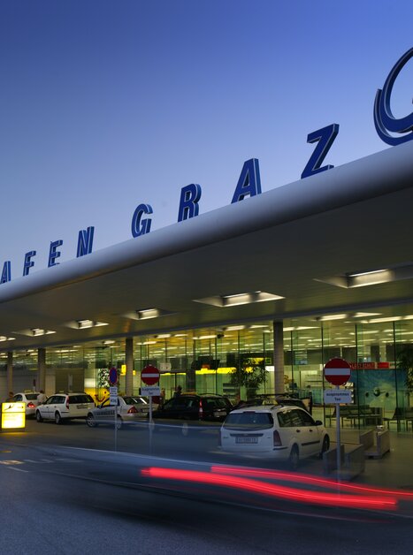 Der Flughafen Graz mit modernen Architekturelementen, beleuchtet bei Dämmerung. | © Graz Tourismus - Harry Schiffer