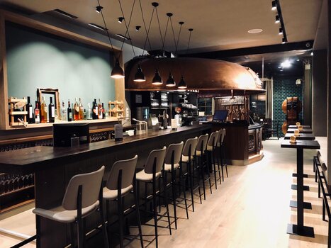 Stylische Bar mit Holztheke, Hockern und Dekoration auf Regalen im Restaurant Gösserbräu. | © Gösserbräu