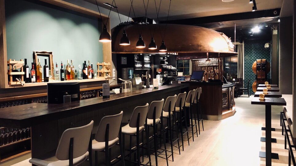 Stylische Bar mit Holztheke, Hockern und Dekoration auf Regalen im Restaurant Gösserbräu. | © Gösserbräu